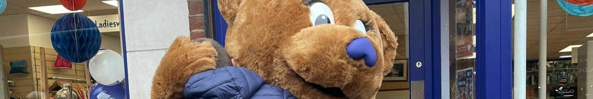 harry-the-bear-mascot-hugs-person-outside-shop
