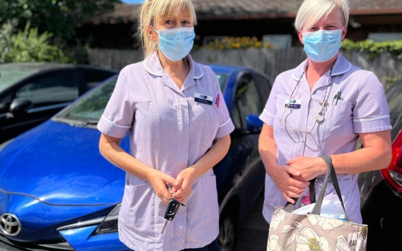 two-community-health-care-assistants-stand-by-their-car