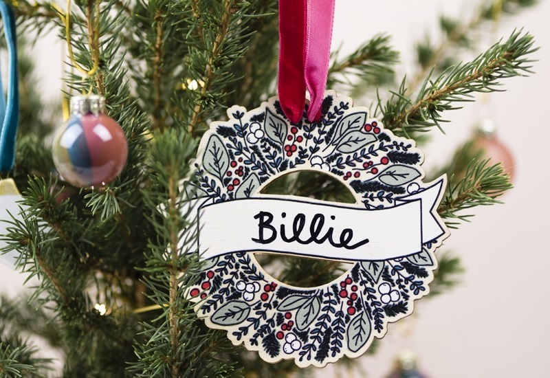 a-wooden-wreath-hanging-on-ribbon-from-a-christmas-tree