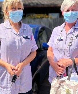 two-community-health-care-assistants-stand-by-their-car